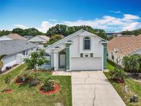 Charming home features a well-maintained lawn, white paint, and a two-car garage with a lush, green landscape at 1034 Copenhagen Way, Winter Garden, FL 34787
