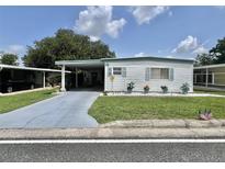 Charming single-story home with carport, well-maintained lawn, and beautiful landscaping at 105 Avocado Cv, Leesburg, FL 34748