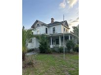 Exterior of a two-story home with a covered front porch and classic architectural details needing a bit of TLC at 110 S Trowell Ave, Umatilla, FL 32784