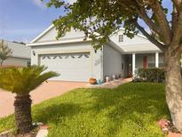 Charming single-story home with a well-manicured lawn, lush landscaping, and a brick-paved driveway at 1180 Mesa Verde Ct, Clermont, FL 34711