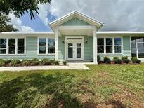 Charming single-story home with light green siding, white trim, and landscaped front yard at 12110 Grand Oak Ln, Oxford, FL 34484