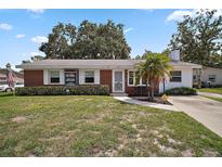 Charming single-story brick home featuring a well-maintained lawn and quaint landscaping at 1301 Cambridge Dr, Leesburg, FL 34748