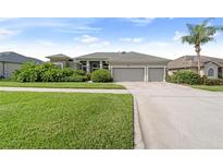 Charming single-story home with a lush, landscaped front yard and a three-car garage at 1351 Legendary Blvd, Clermont, FL 34711