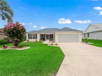 Charming single-story home featuring a well-manicured lawn and a two-car garage at 17824 Se 87Th Bourne Ave, The Villages, FL 32162