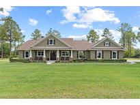Inviting single story home featuring an expansive lawn, rocking chair front porch, and neutral exterior at 23247 Lake Seneca Rd, Eustis, FL 32736