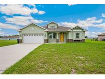 Charming single-story home with a two-car garage, lush green lawn, and bright yellow front door at 2495 Se 75Th Blvd, Bushnell, FL 33513