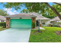 Charming single-story home with a green garage door, brick accents and well-maintained lawn at 25025 Cranes Roost Cir, Leesburg, FL 34748