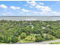Expansive aerial view of canal front property with mature trees and a large springhead on a sunny day at 27113 Robertson Rd, Yalaha, FL 34797