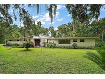Sprawling front yard and charming single-story home amidst lush landscaping and mature trees at 27113 Robertson Rd, Yalaha, FL 34797