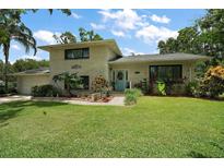 Charming two-story home with a well-manicured lawn, mature trees and a brick facade at 27212 Orange Ave, Yalaha, FL 34797