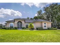 Spacious home with a well-manicured lawn, lush greenery, and charming architectural details at 29152 David Ct, Tavares, FL 32778