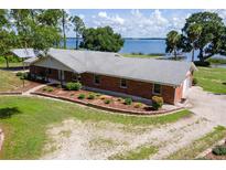 Beautiful lakefront home featuring a brick exterior and well-manicured front yard landscaping at 38314 Echols Rd, Leesburg, FL 34788