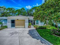 Charming home featuring a decorative driveway, attached garage, and manicured lawn with lovely flower beds at 409 Westwood Dr, Leesburg, FL 34748
