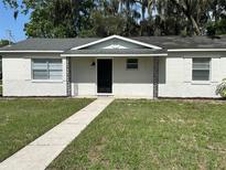 Charming single-story home with a brick exterior, black front door, and landscaped front yard at 460 Wisteria Ave, Umatilla, FL 32784
