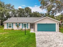 Charming single-story home featuring a well-manicured lawn, teal garage door, and complementary teal shutters at 4800 Tara View Rd, Leesburg, FL 34748