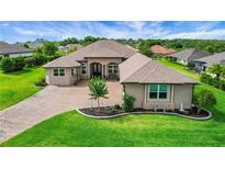 Beautiful one-story home with a brick driveway, manicured lawn, and lush landscaping at 6008 Apex Way, Lady Lake, FL 32159