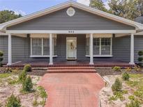 Charming single-story home featuring a brick pathway and inviting front porch with stately white columns at 604 Ponderosa Dr, St Cloud, FL 34769