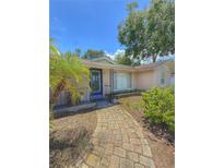 Charming entrance with blue door, and paved walkway surrounded by lush landscaping at 100 W Idlewild Ave, Eustis, FL 32726