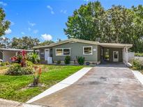 Charming single-story home with a well-maintained lawn, colorful flowers, and a concrete driveway leading to a covered carport at 1156 Capella Dr, Tavares, FL 32778