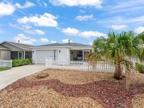 Charming home featuring a well-maintained front yard with a decorative rock garden and a white picket fence at 1199 Mathews Ln, The Villages, FL 32162