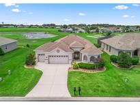 Well-maintained single-story home with a lush lawn, attached two-car garage, and manicured landscaping at 12198 Se 176Th Loop, Summerfield, FL 34491