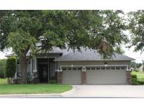 Charming home with a well-manicured lawn, mature tree, and three-car garage at 1355 Misty Glen Ln, Clermont, FL 34711