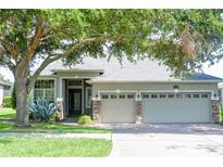 Charming single-story home featuring a three-car garage and lush front yard landscaping with mature tree at 1355 Misty Glen Ln, Clermont, FL 34711