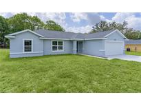 Charming single-story home featuring a lush green lawn and attached two-car garage at 14611 Se 95Th Ct, Summerfield, FL 34491