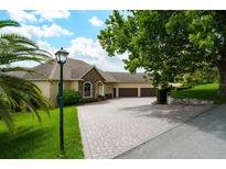 Stunning single-Gathering home showcasing manicured landscaping, paver driveway, and a three-car garage at 18008 Victorian Dr, Clermont, FL 34715