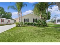 Charming home featuring lush landscaping, palm trees, and well-maintained lawn at 1815 Kaufman Cir, Lady Lake, FL 32159
