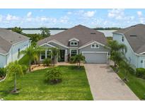 Charming single-story home with a well-manicured lawn, palm trees, and a brick driveway leading to a two-car garage at 2330 Nuthatch St, St Cloud, FL 34771
