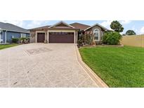 Charming single-story home featuring a beautifully landscaped front yard, patterned driveway, and a three-car garage at 2585 Constance Ct, The Villages, FL 32163