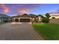 Charming single-story home featuring a beautifully landscaped front yard, patterned driveway, and a three-car garage at 2585 Constance Ct, The Villages, FL 32163