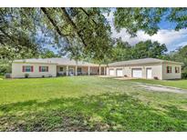 Sprawling ranch home with an oversized lawn, long porch, attached guest home, and three-car garage at 30342 Vitex Ave, Eustis, FL 32736