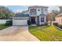 Charming two-story home featuring a balcony, stone accents, a well-manicured lawn, and a two car garage at 33316 Irongate Dr, Leesburg, FL 34748