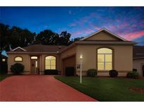 Charming single-story home featuring a brick driveway, well-manicured lawn, and lovely landscaping at 5008 Sawgrass Lake Cir, Leesburg, FL 34748