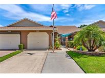 Charming home featuring an American flag, manicured landscaping and attached two car garage at 5512 Rosewall Cir, Leesburg, FL 34748