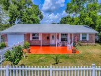 Charming single-story brick home featuring a welcoming front porch with rocking chairs at 564 Lancaster Ave, Orange City, FL 32763