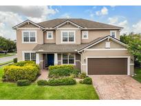 Charming two-story home with well-maintained landscaping and a brick driveway leading to a two-car garage at 752 Sandy Bar Dr, Winter Garden, FL 34787