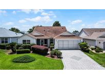 Charming single-story home featuring a well-manicured lawn and a neatly paved driveway at 8960 Se 178Th Muirfield Pl, The Villages, FL 32162