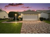 Charming single-story home featuring a brick driveway, well-manicured lawn, and an attached two-car garage at 1007 Diego Ct, The Villages, FL 32159