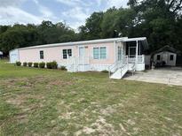 Charming single Gathering home featuring a screened porch, ramp and two storage buildings at 10905 Se 127Th Ln, Belleview, FL 34420