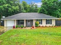 Charming single-story home featuring lush landscaping, a gray roof and a welcoming entrance, complemented by a well-maintained front yard at 12181 Se 87Th Ct, Belleview, FL 34420