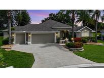 Charming single-story home with a three-car garage, beautiful landscaping, and mature palm trees in a suburban neighborhood at 1335 Eureka Mill Run, The Villages, FL 32162