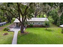 Inviting home boasts lush lawn, stone accents, and a metal roof, nestled under mature trees with Spanish moss at 1436 Spring Lake Rd, Fruitland Park, FL 34731