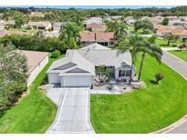 Beautiful home showcasing meticulous landscaping, a gray roof, and a spacious three-car driveway at 2455 Five Forks Trl, The Villages, FL 32162
