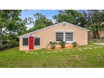 Charming one-story home featuring a red front door, well-maintained lawn, and mature trees at 256 Carroll St, Clermont, FL 34711