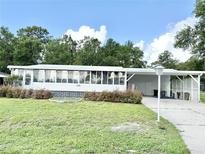 Well-maintained home with bright white exterior, enclosed porch, and carport at 2585 Karen Dr, Mount Dora, FL 32757