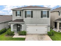 Two-story home featuring a two-car garage, neutral gray paint and minimalist landscaping in a suburban neighborhood at 30422 Pintail Dr, Leesburg, FL 34748