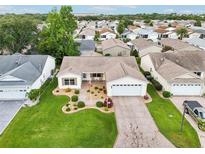 Beautiful aerial view of single-story home with manicured lawn and stone driveway in a lovely neighborhood at 3460 Idlewood Loop, The Villages, FL 32162